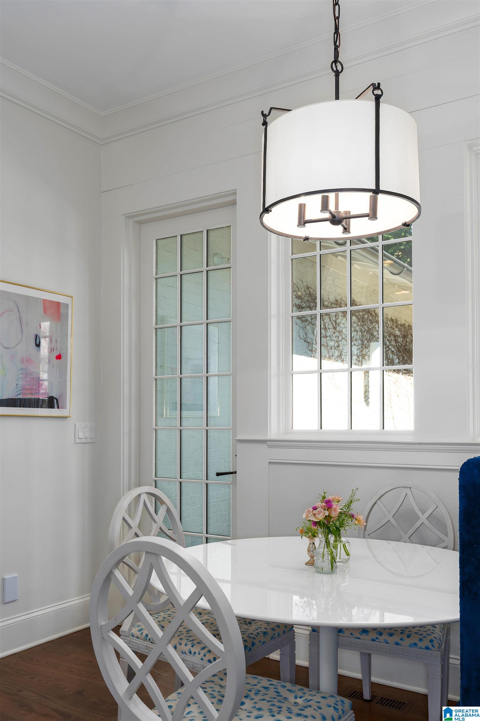 Dining area with a white table, blue-patterned chair cushions, and a large pendant light.