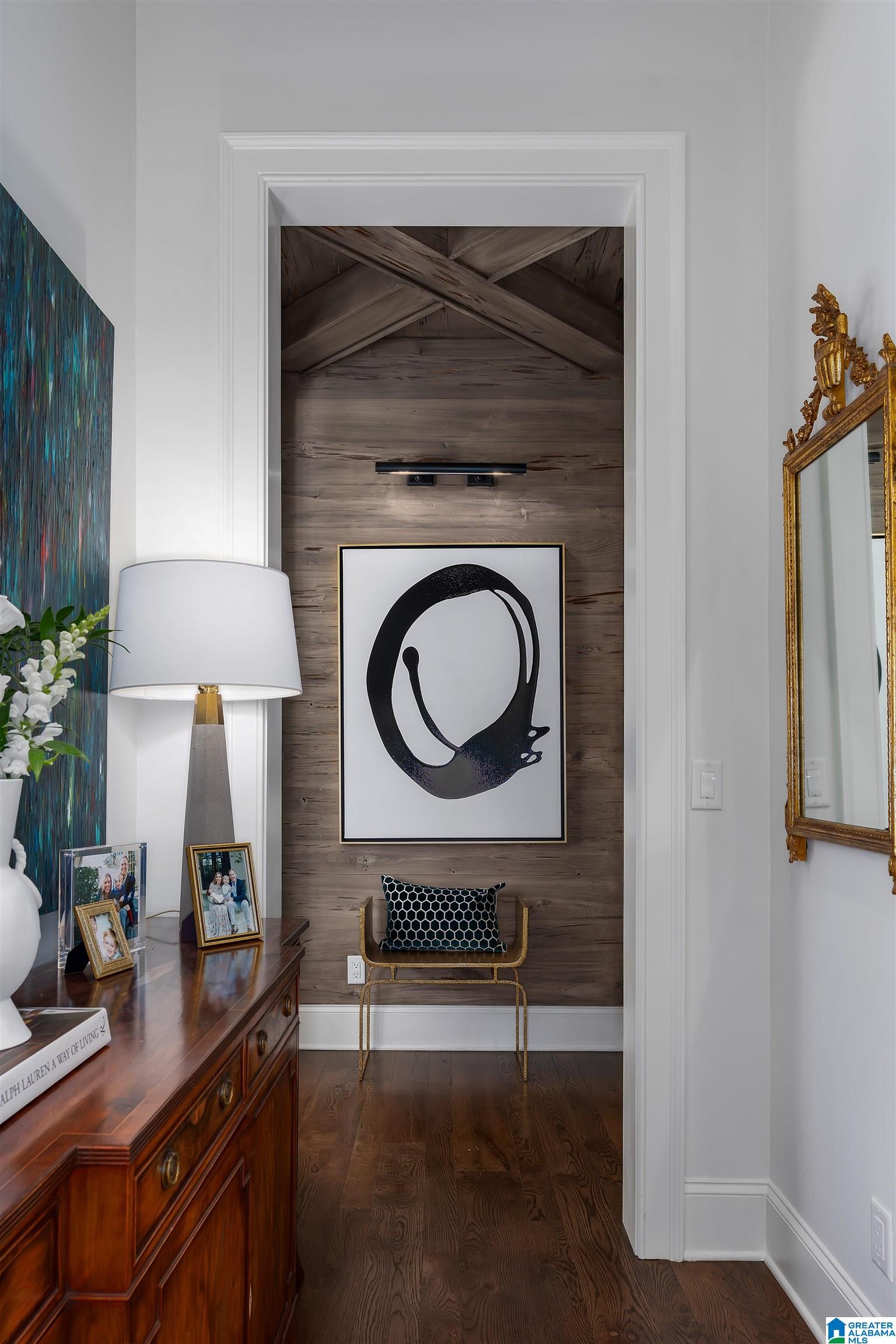 Hallway with a weathered wood feature wall, abstract artwork, console table, and ornate gold-framed mirror.