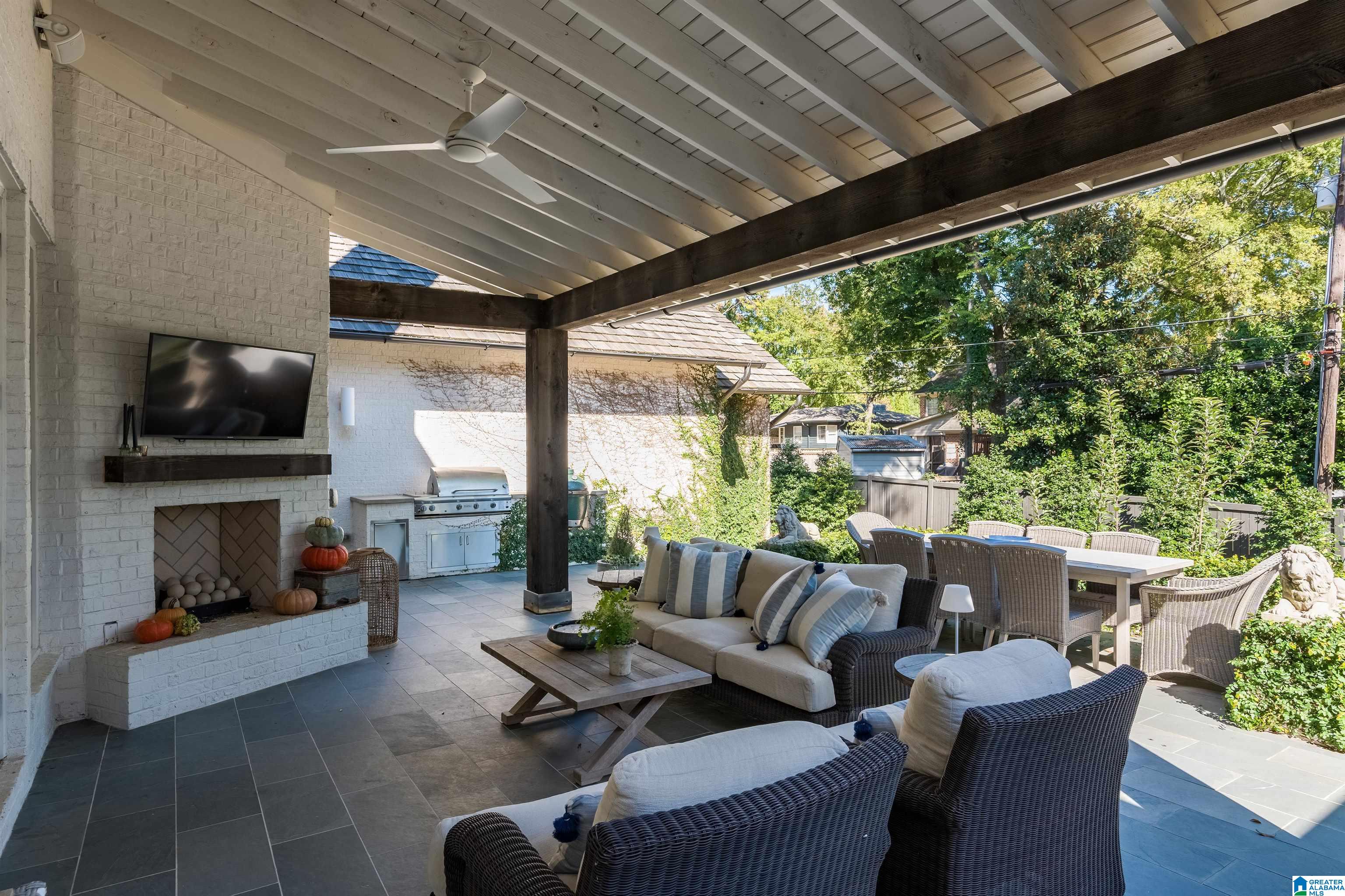 Covered patio with a brick fireplace, built-in grill, and wicker lounge seating.
