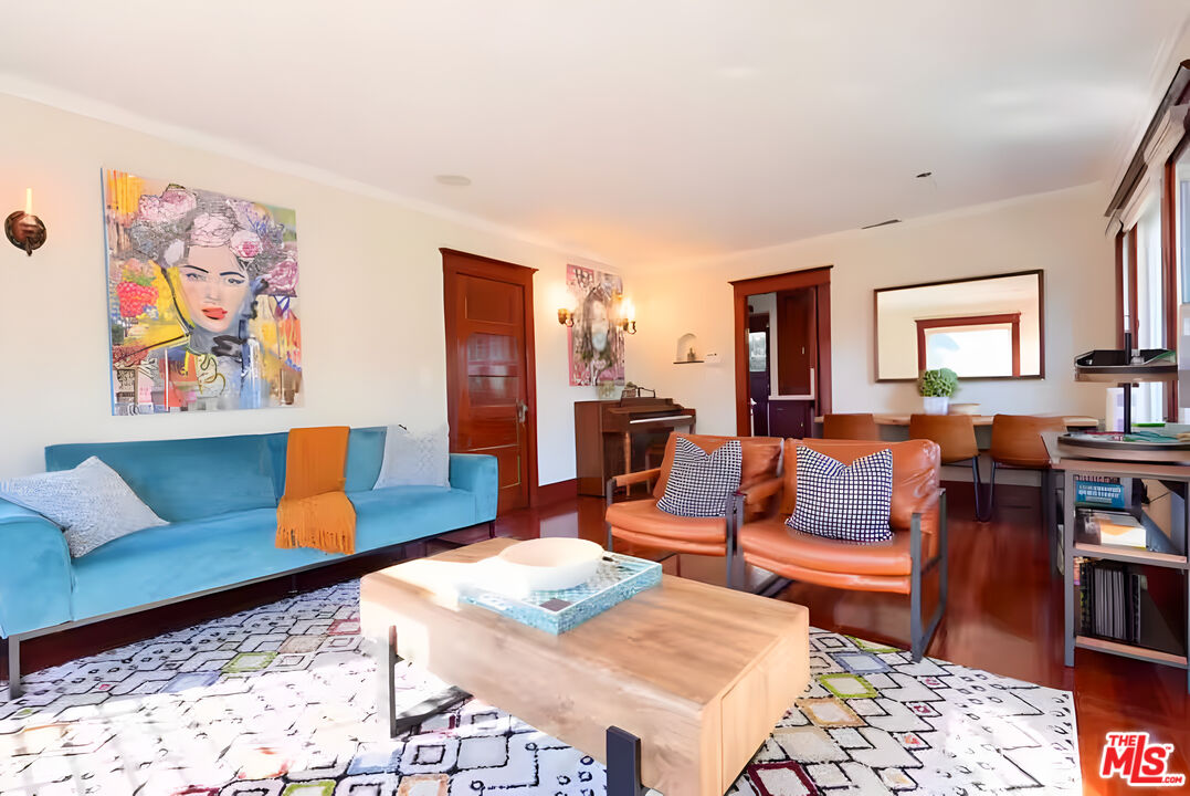 Living room with a turquoise sofa, rust-colored leather chairs, and a patterned rug.