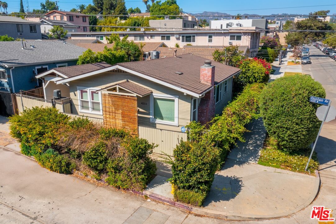 Aerial view of a single-story home with a brown gabled roof, leafy front garden, and Fountain Avenue street sign.