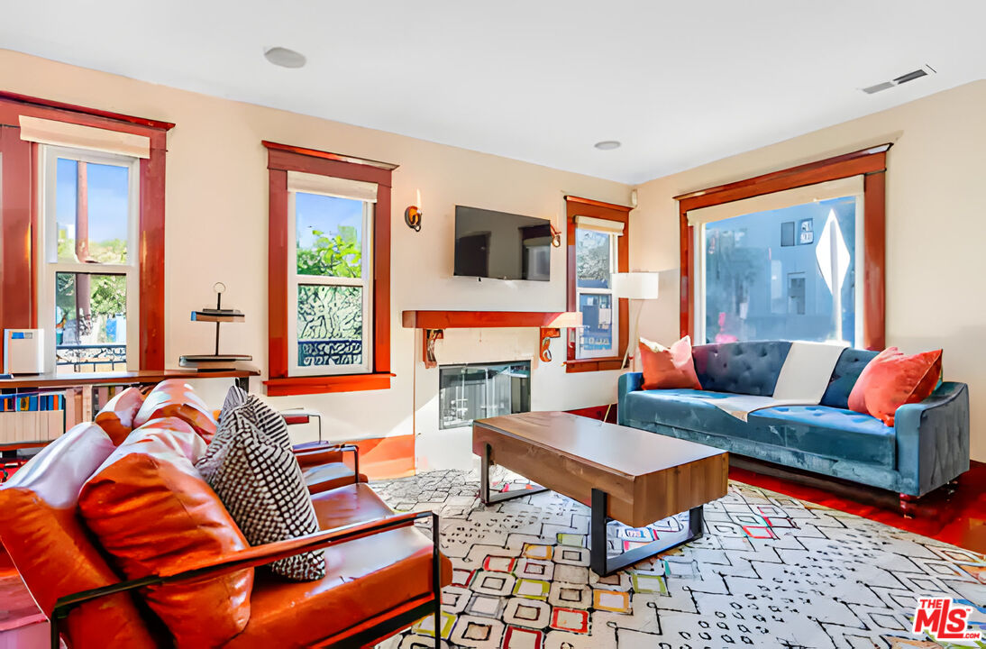 Furnished living room with a fireplace, red-trimmed windows, blue sofa, and orange leather chairs.