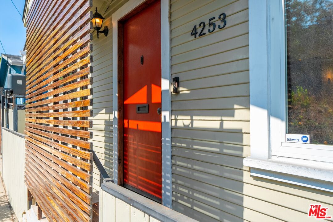 Home entrance with a red front door and wooden slat privacy screen.