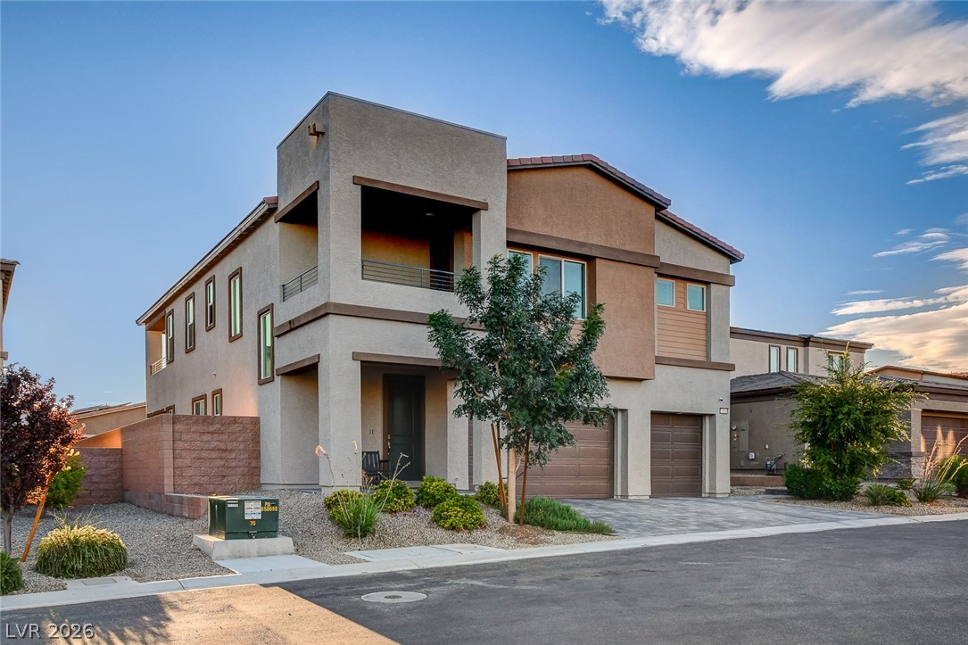 Modern two-story stucco home with a balcony, double garage, and desert landscaping.