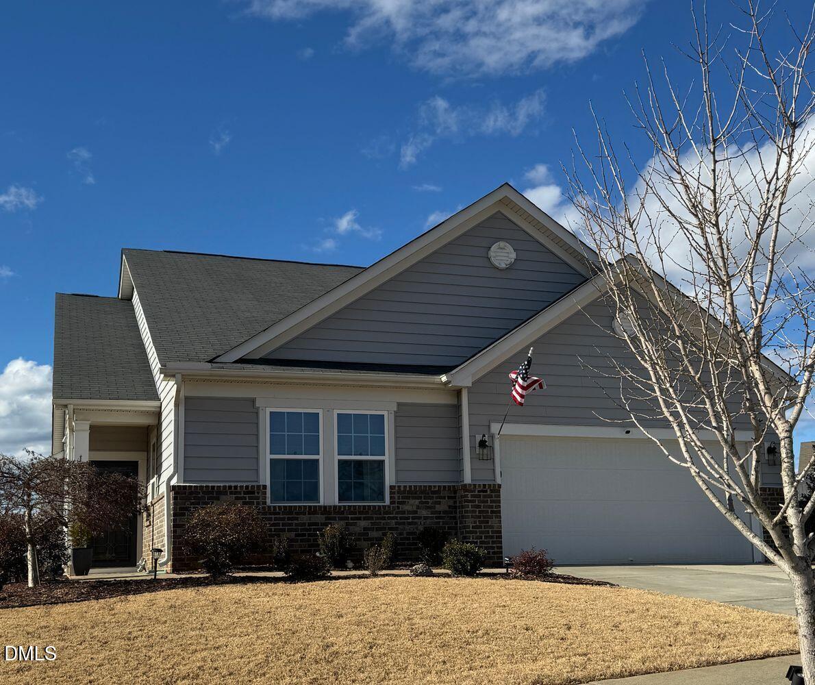 Gray-sided home with brick accents, a white garage door, and an American flag.