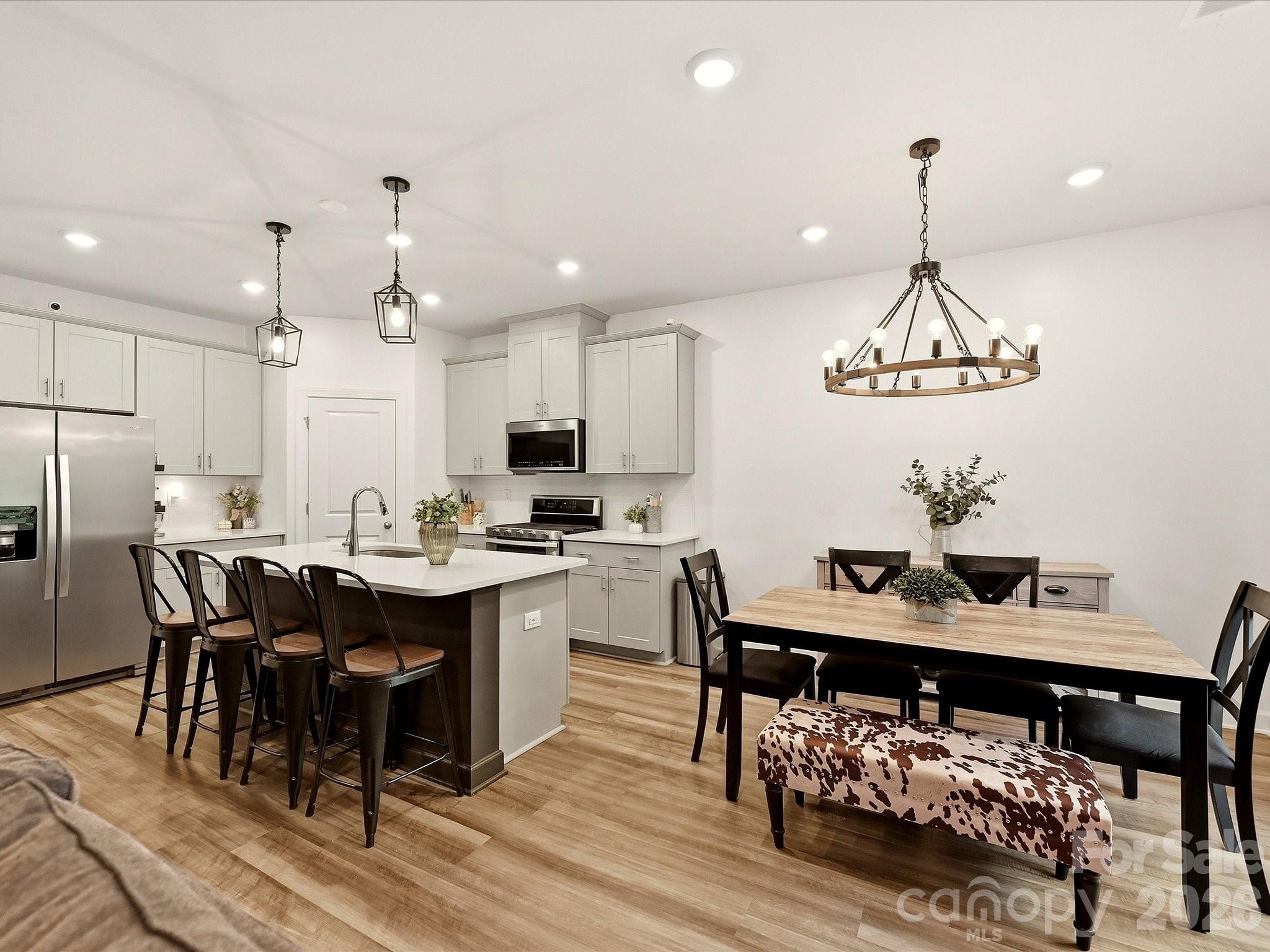 Open-plan kitchen and dining area with a large island, stainless steel appliances, and a chandelier.