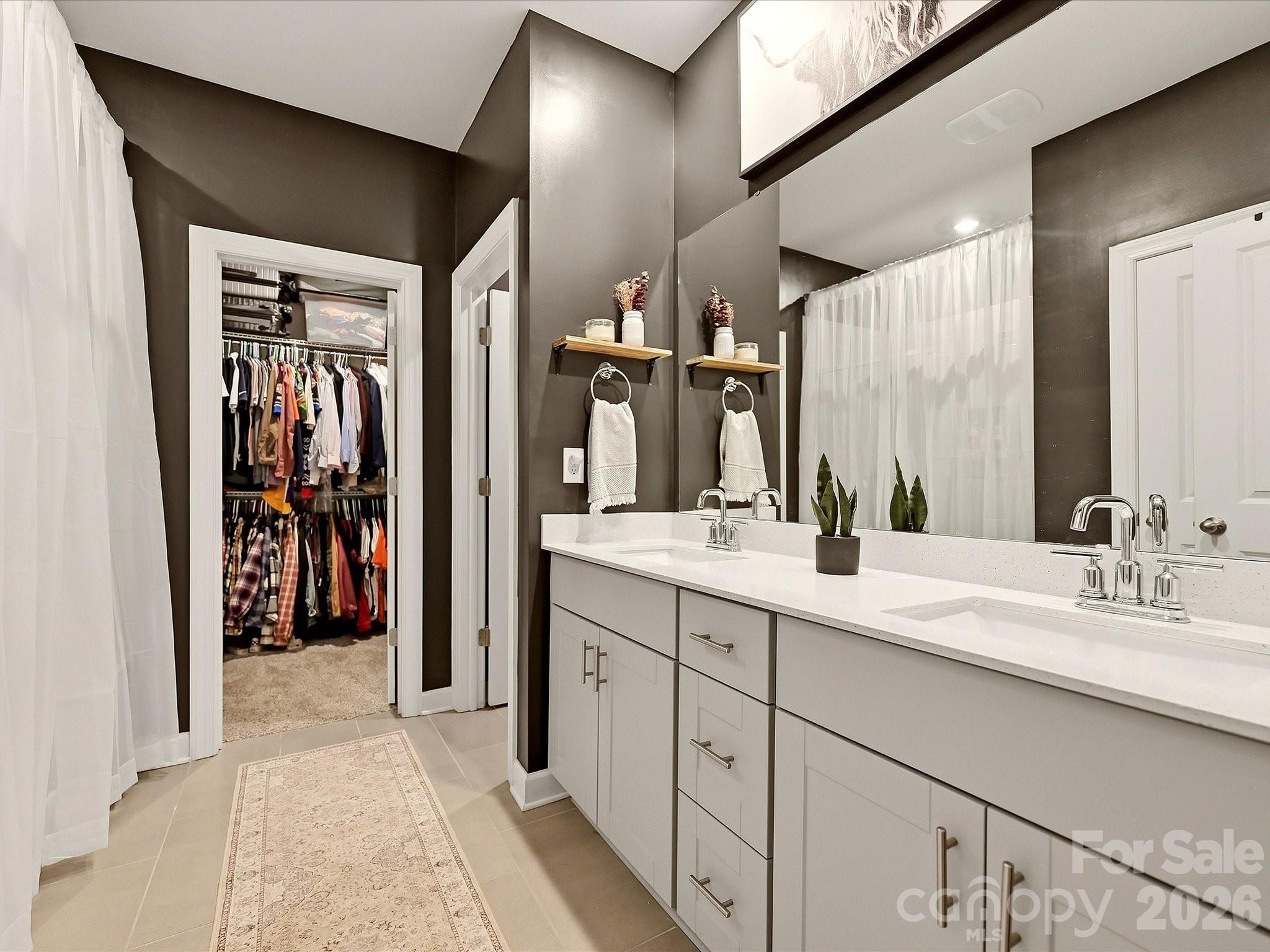 Bathroom with a white double vanity and an open walk-in closet.