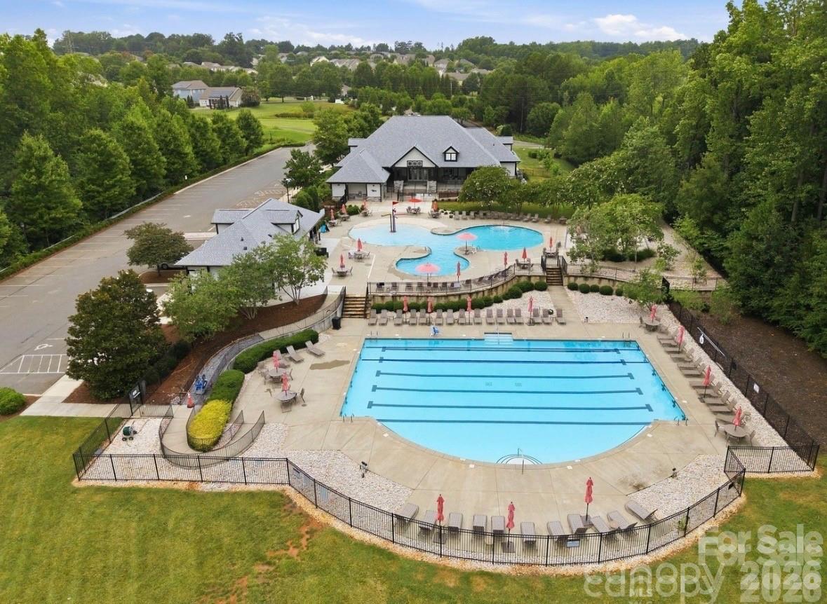 Aerial view of a neighborhood recreation area with two swimming pools, clubhouse, and surrounding trees.