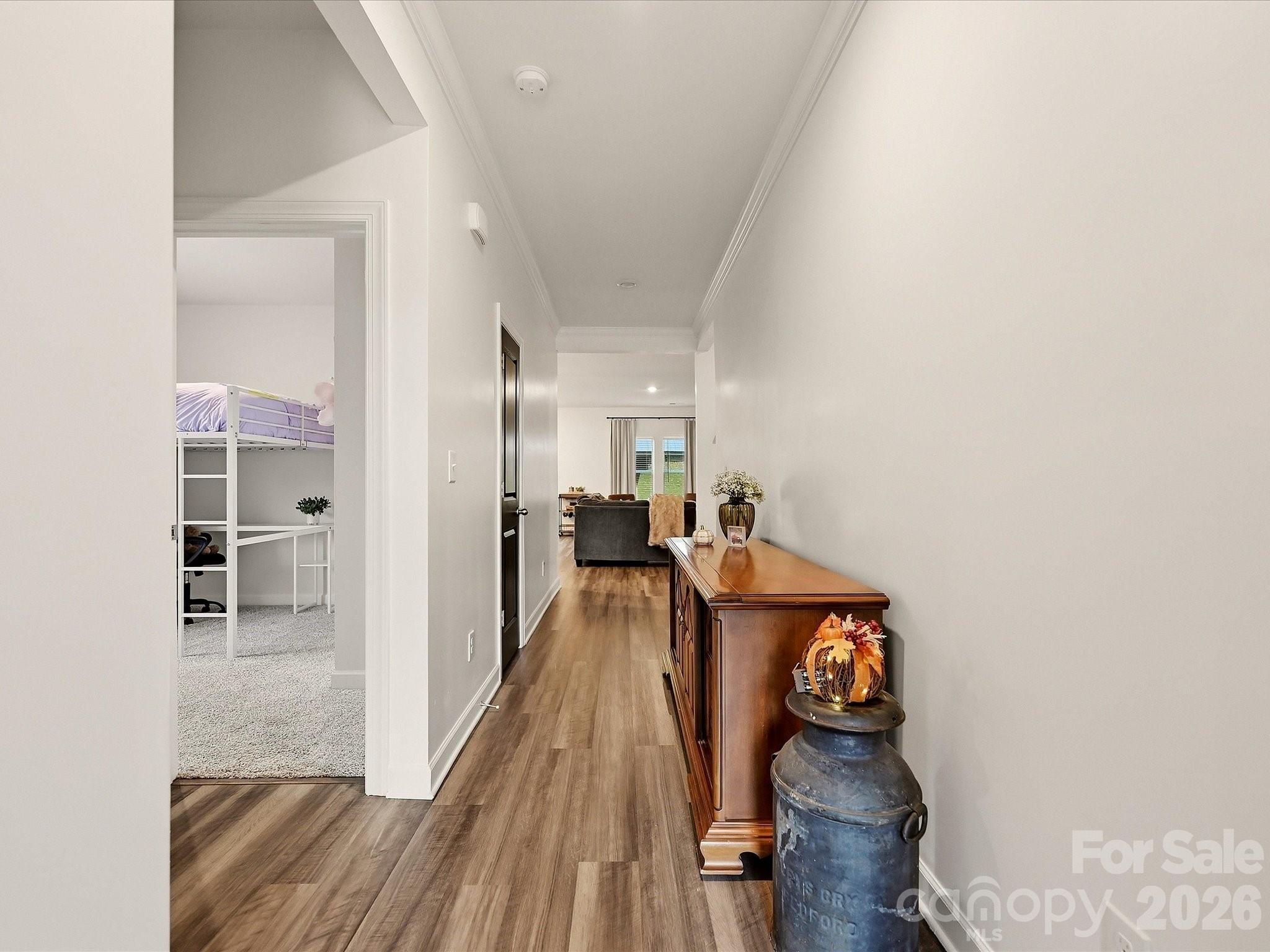 Furnished hallway with wood-look flooring, a wooden console table, and an open view into a loft-bed bedroom.