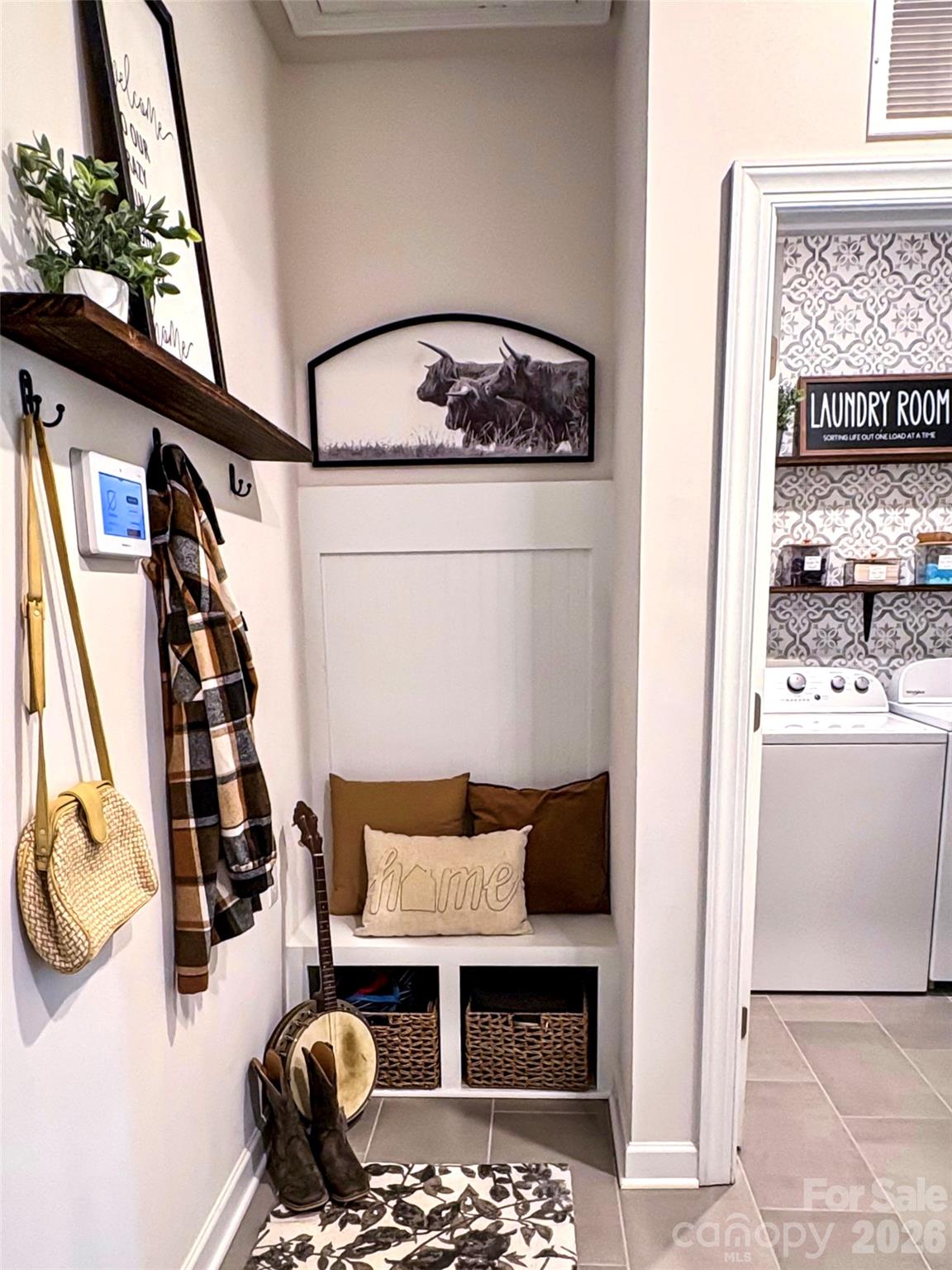 Entry nook with built-in bench, woven baskets, wall hooks, and a doorway to the laundry room.