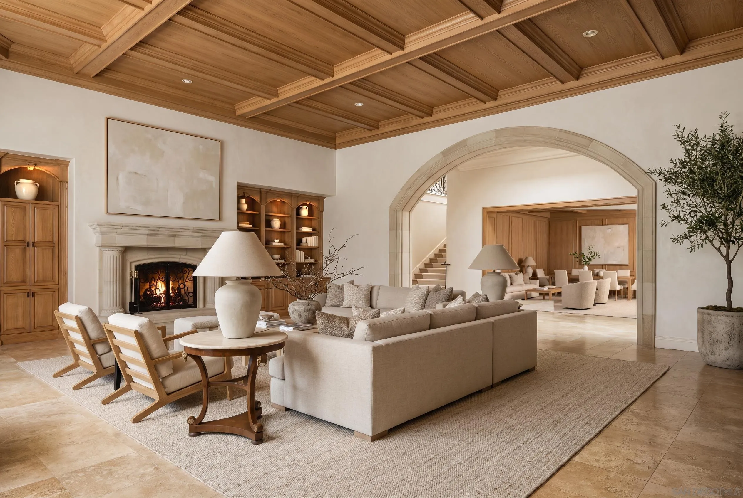 Living room with a coffered wood ceiling, stone fireplace, and arched opening to the dining room.