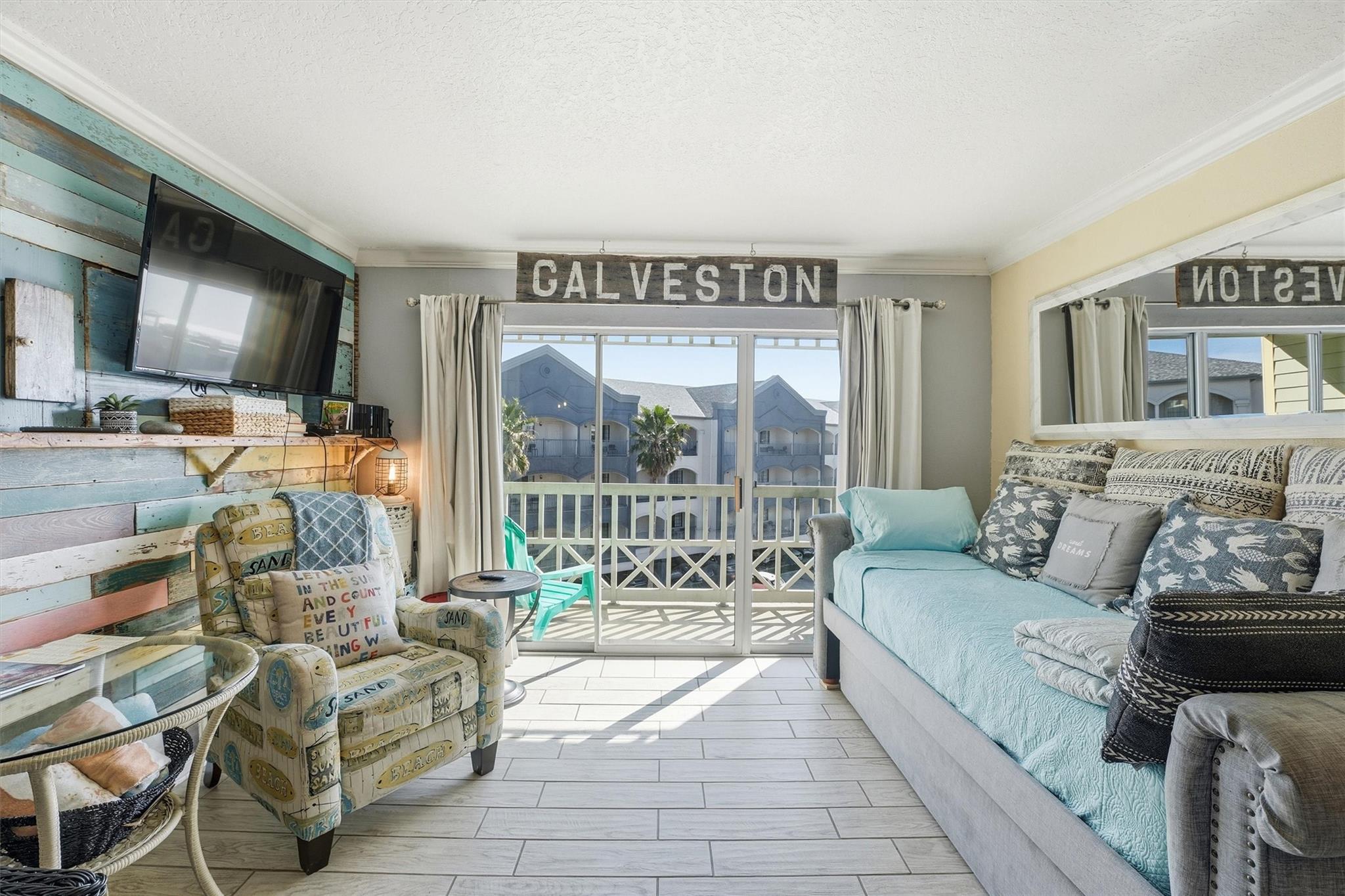 Furnished living room with a turquoise sofa, patterned armchair, and sunny balcony doors.