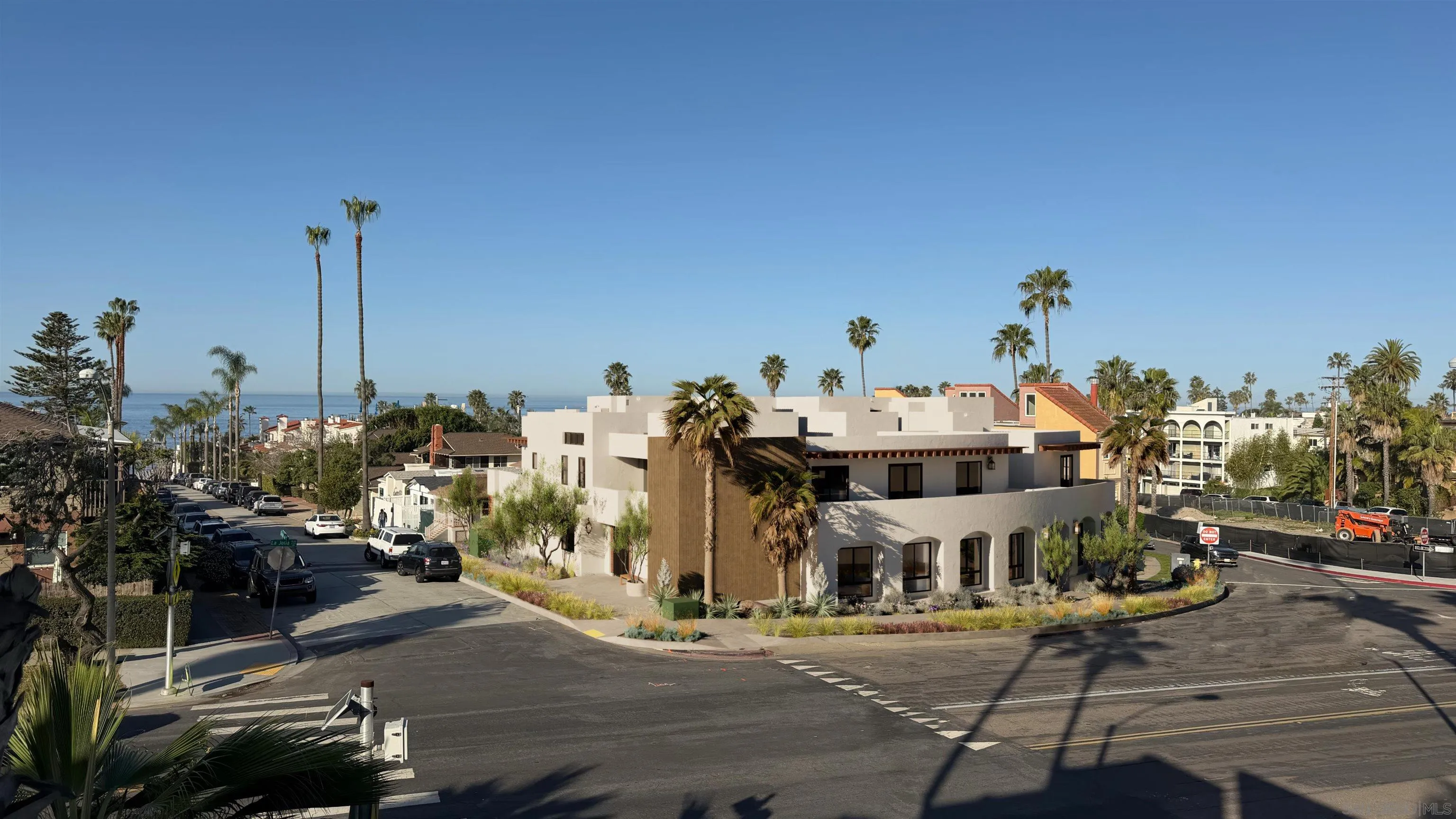 Modern corner building in La Jolla, with palm trees and a glimpse of the Pacific Ocean.