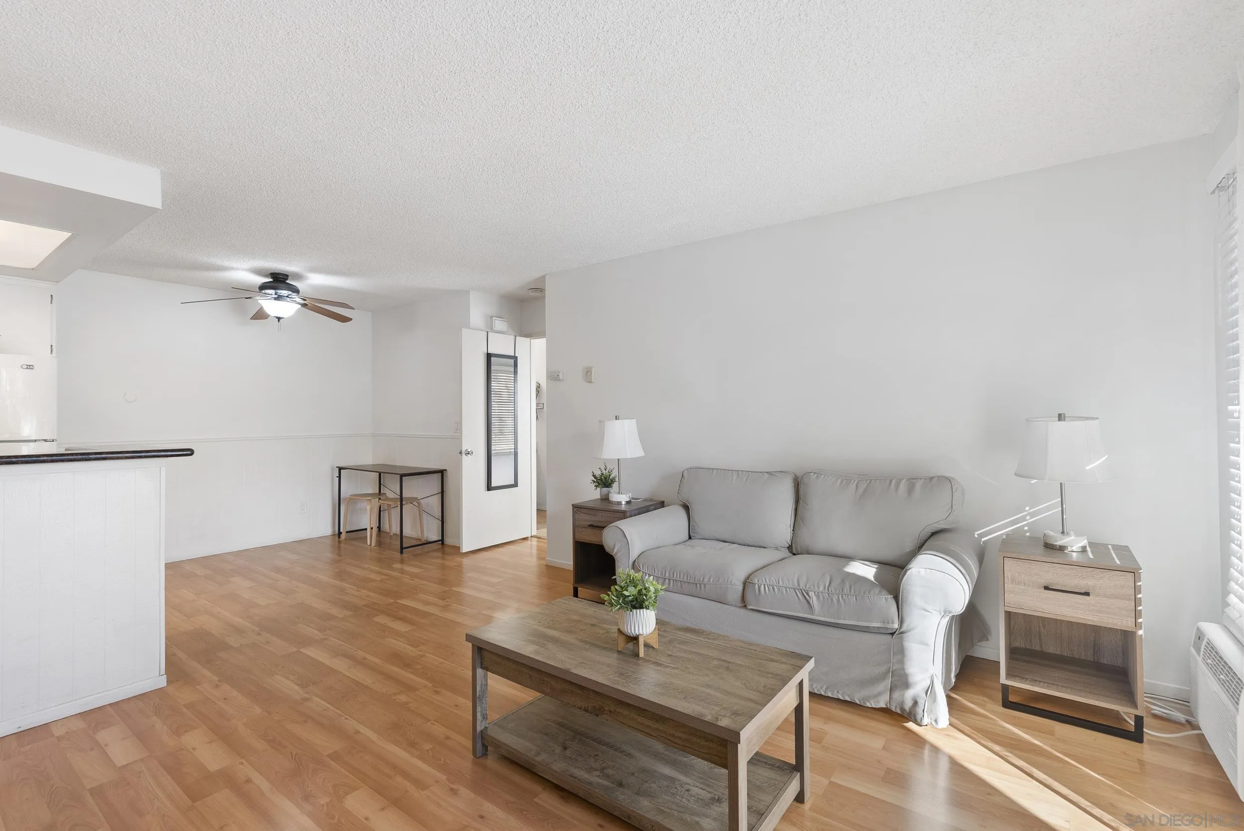 Furnished condo living room with a gray sofa, wood coffee table, and light wood floors.