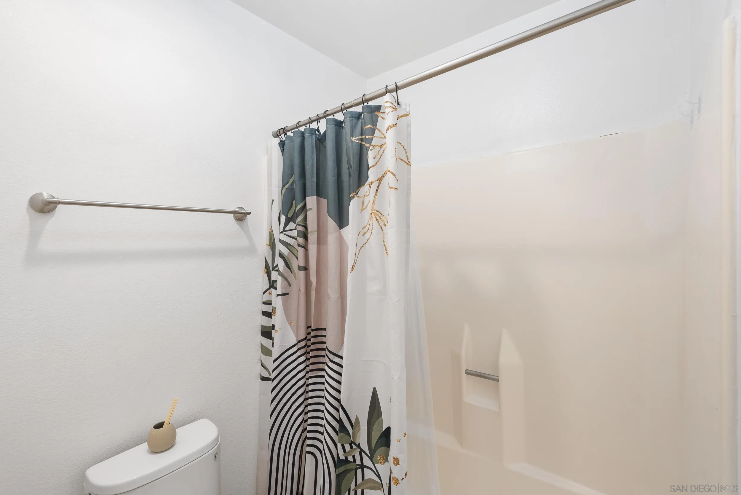 Bathroom with a patterned shower curtain, white tub, and toilet.