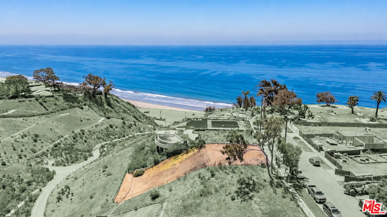 Cleared coastal hillside lot overlooking the ocean, with nearby homes under construction.