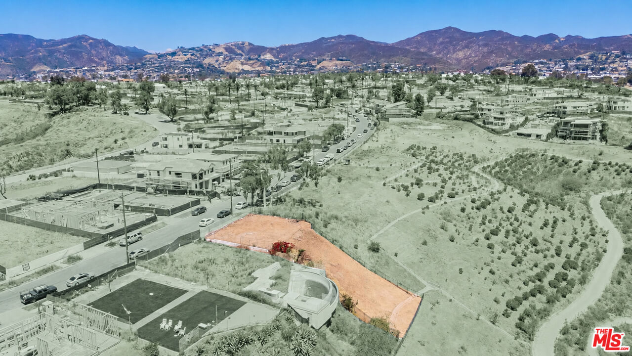Vacant parcel highlighted in orange among homes, with mountains in the distance.