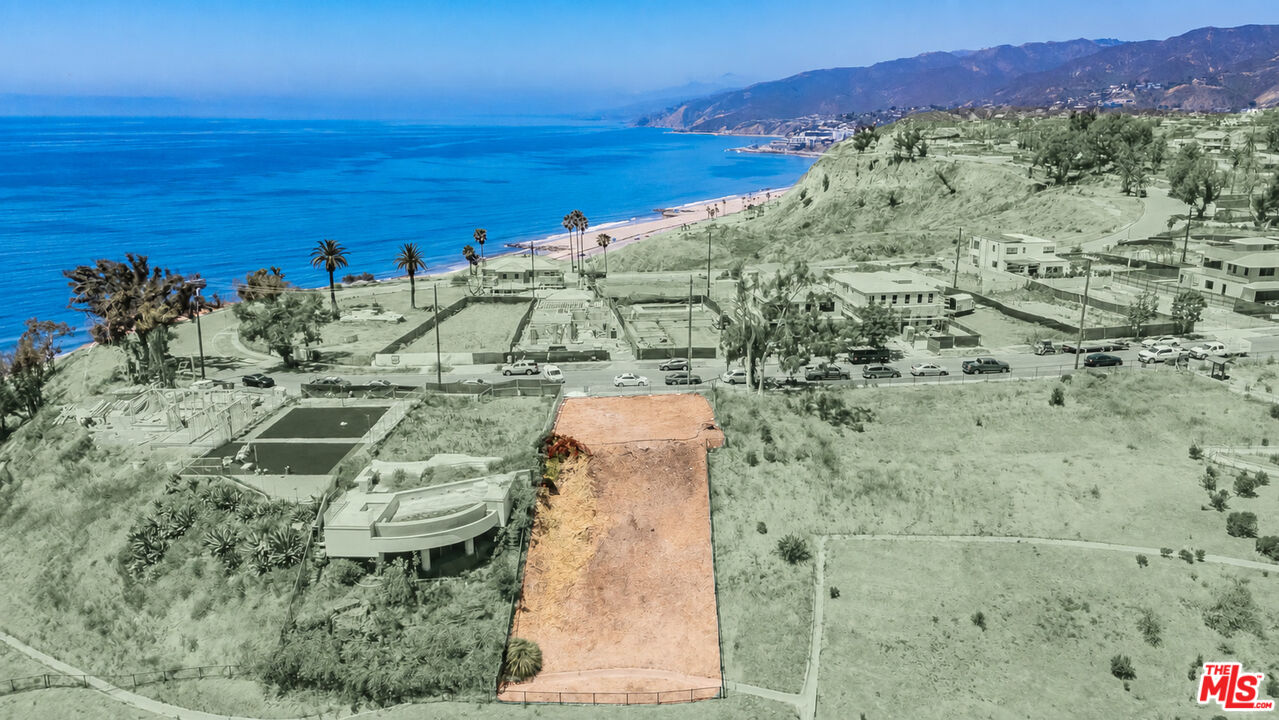Vacant hillside lot outlined in orange, overlooking the Pacific Ocean with mountains beyond.