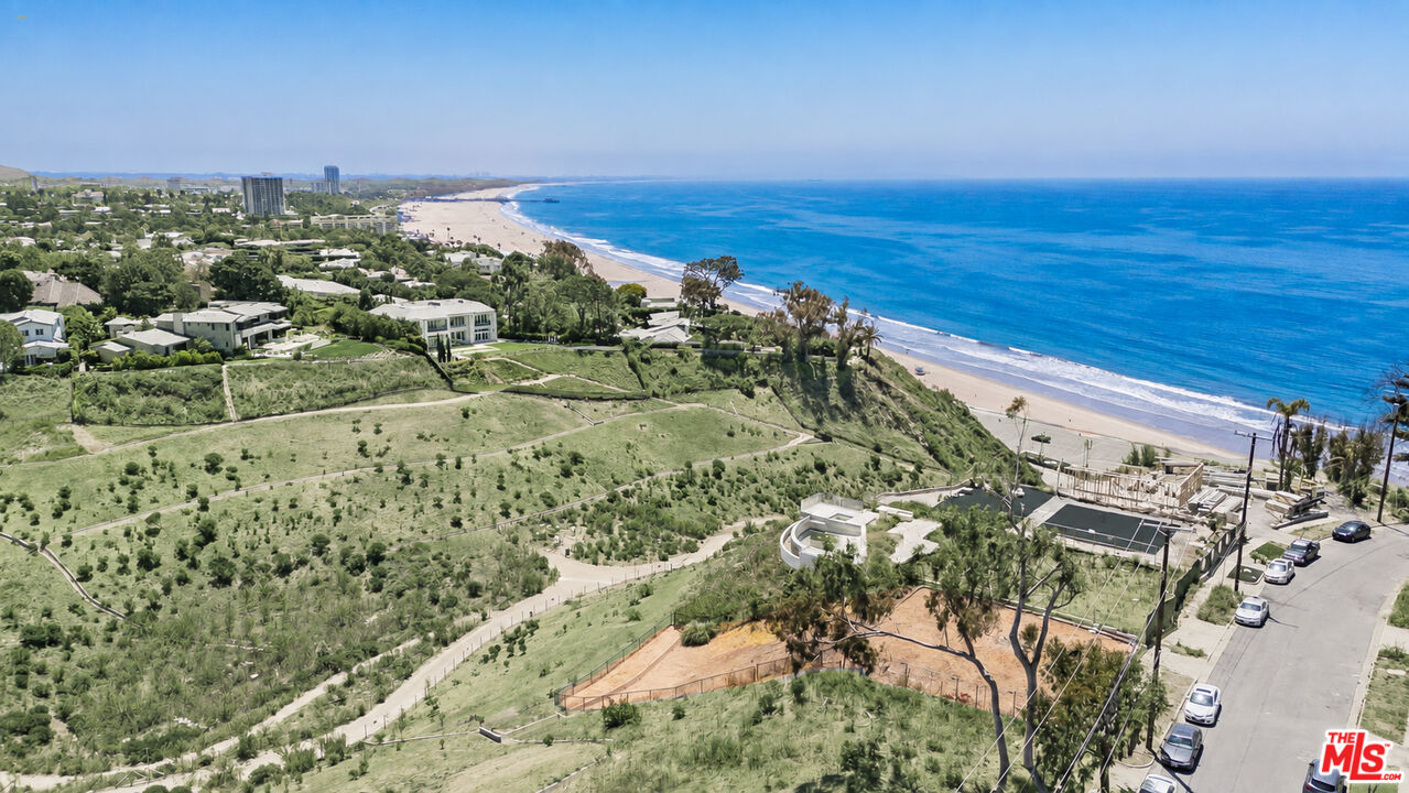 Aerial view of a graded coastal parcel above the beach, with Pacific Ocean and nearby homes.