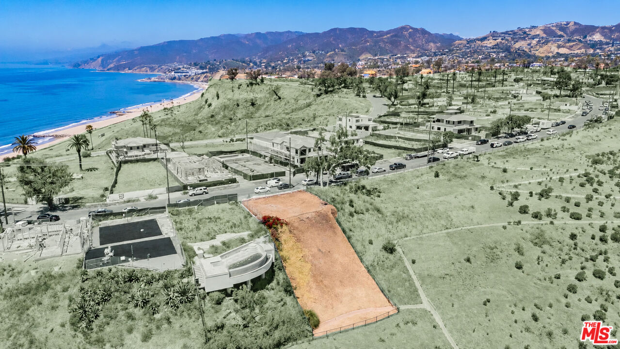 Vacant hillside lot highlighted in orange, with the Pacific coastline and mountains in the distance.