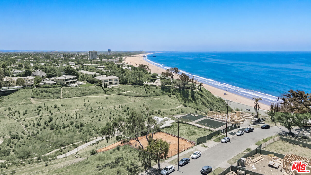 Aerial view of the property above a coastal neighborhood, sandy beach, and Pacific Ocean.