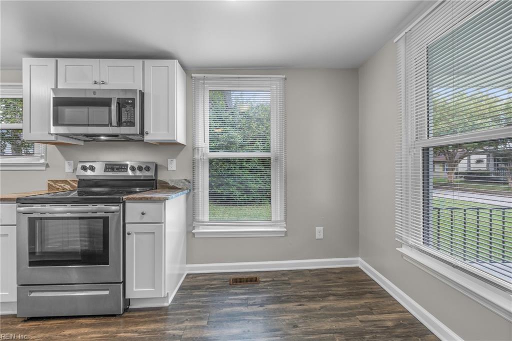 Kitchen with white cabinets, stainless steel appliances, and large windows overlooking the yard.