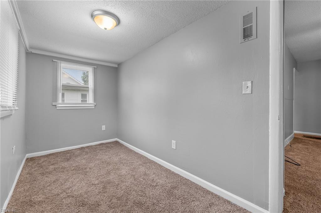 Empty carpeted bedroom with gray walls, two windows, and a ceiling light.