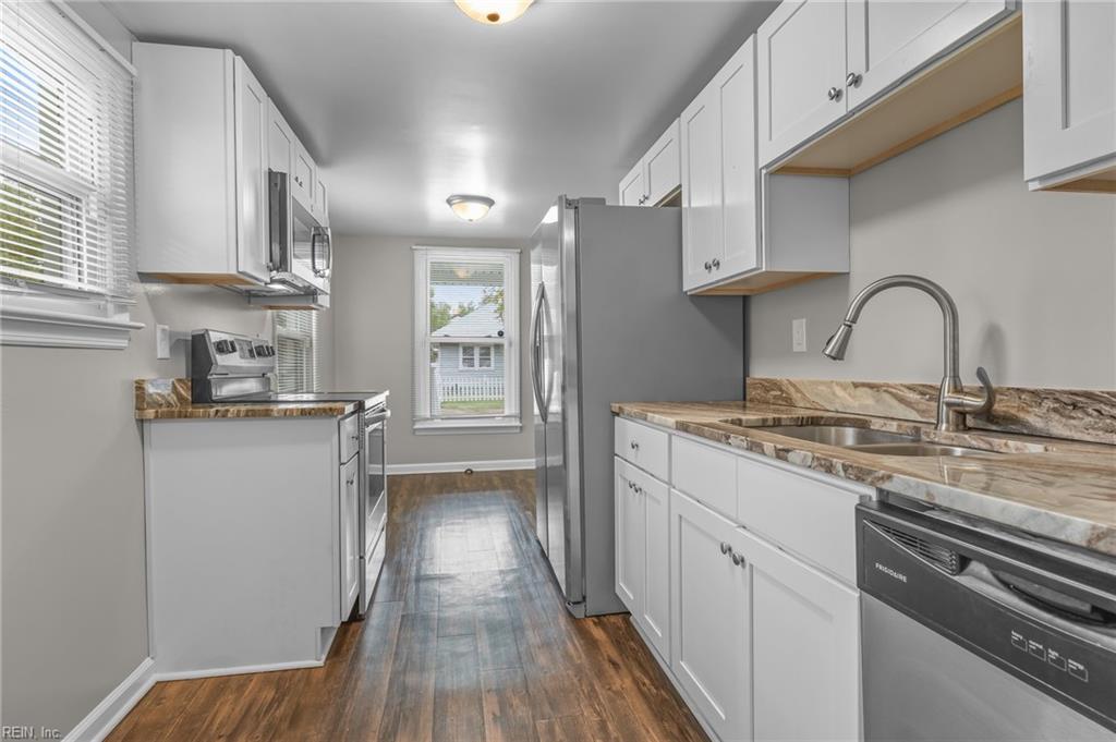 Kitchen with white cabinets, patterned stone counters, stainless steel appliances, and wood-look floors.