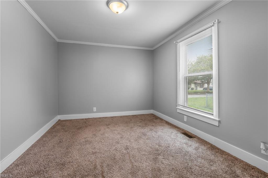 Empty room with gray walls, brown carpet, and a window with white blinds.