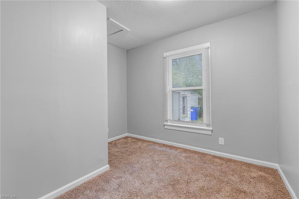 Vacant bedroom with tan carpet, gray walls, and a window with white blinds.