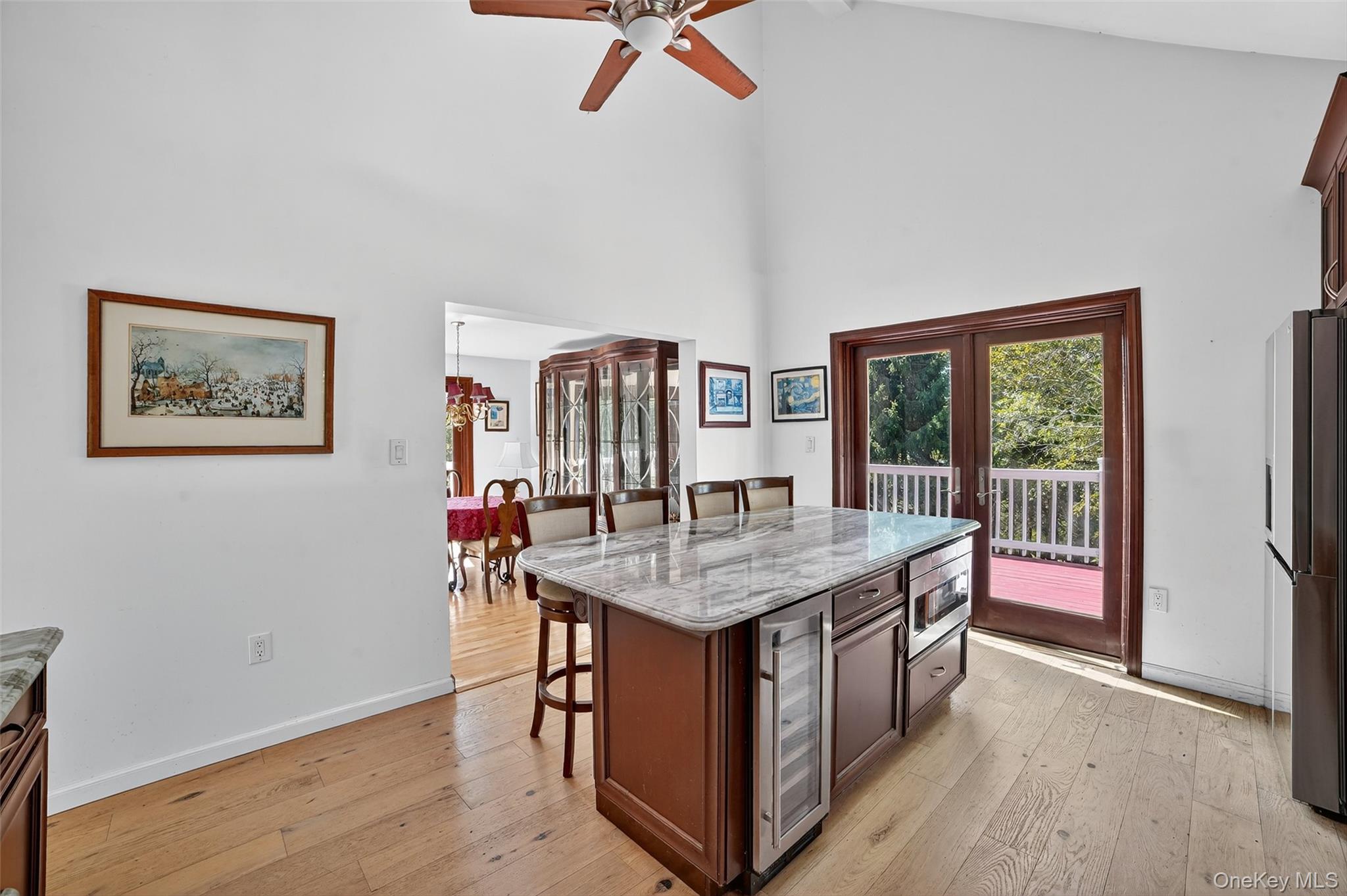 Kitchen with a marble-topped island, built-in wine coolers, and doors opening onto a deck.