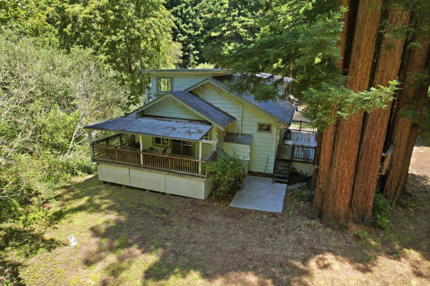 Woodland house with a covered porch and tall redwoods nearby.