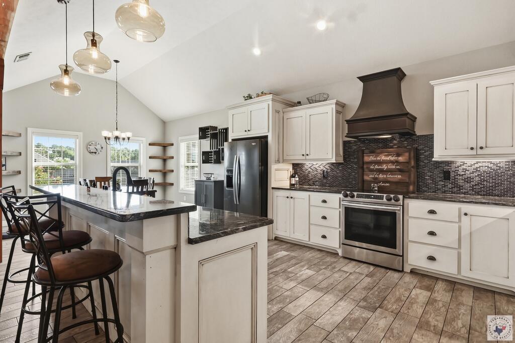 Kitchen with a large dark-stone island, white cabinetry, and stainless steel appliances.