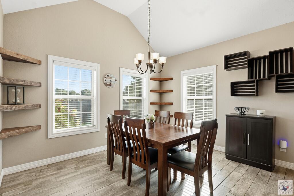 Dining room with a dark wood table and chairs, tile floors, and a chandelier.