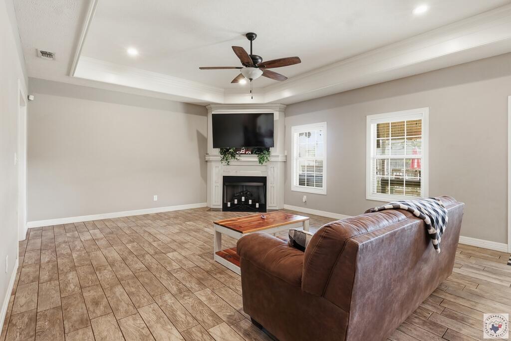 Living room with a leather sofa, tiled floors, fireplace, and wall-mounted television.