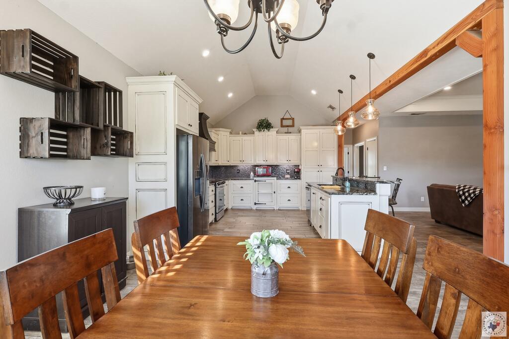 Open kitchen and dining area with white cabinets, a central island, and a large wooden table.