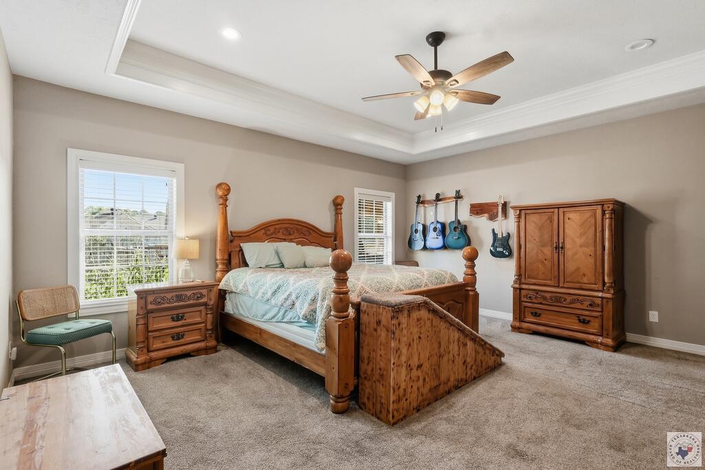 Bedroom with a carved wooden bed, matching furniture, wall-mounted guitars, and a tray ceiling.