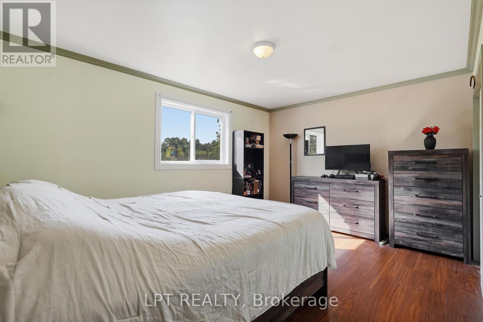 Furnished bedroom with a large bed, dark wood dressers, and hardwood flooring.