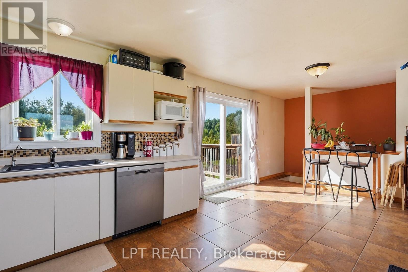 Kitchen with white cabinets, tiled floors, and a breakfast counter beside a sliding glass door.