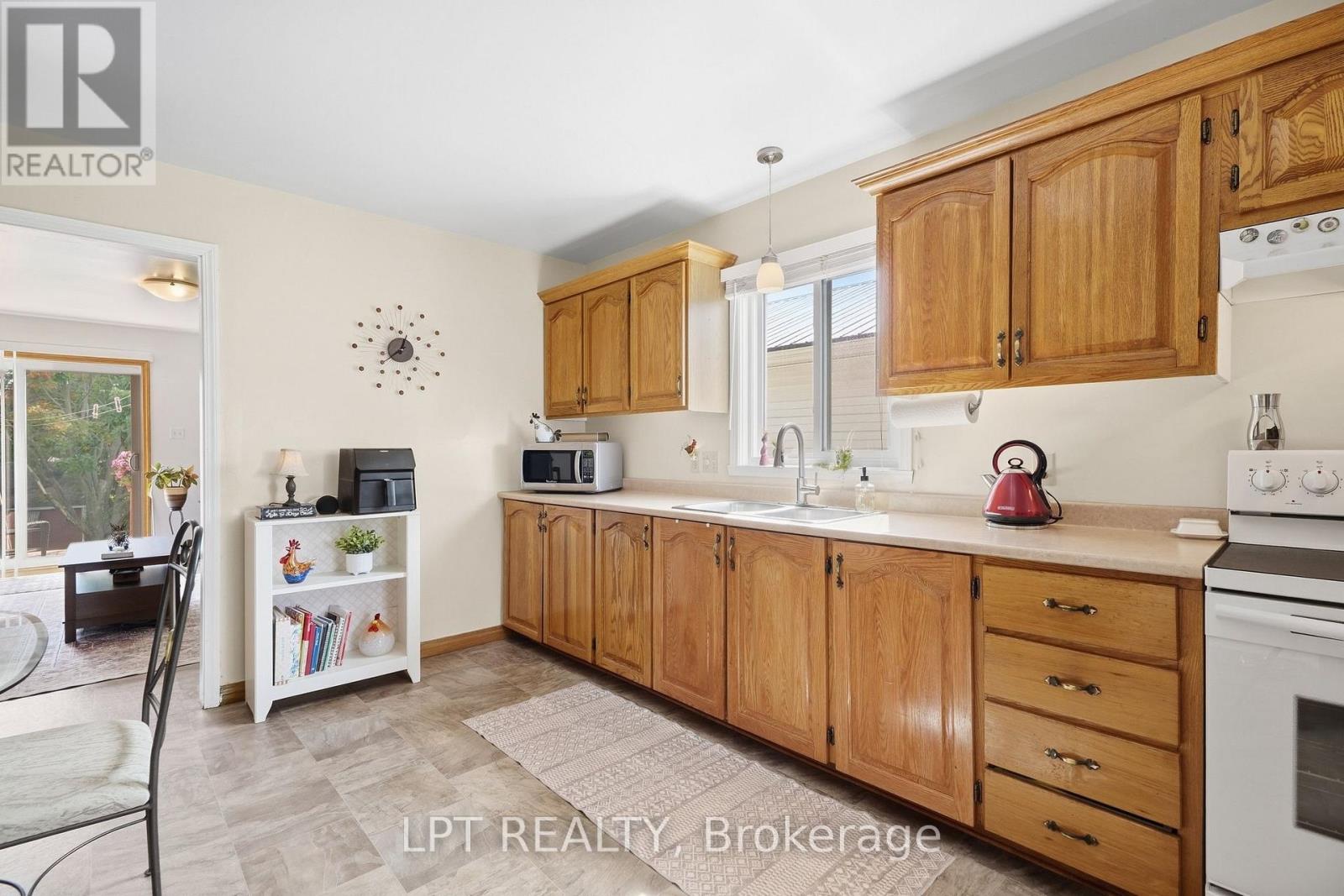 Kitchen with honey-colored wood cabinets, a double sink, and a window above the counter.
