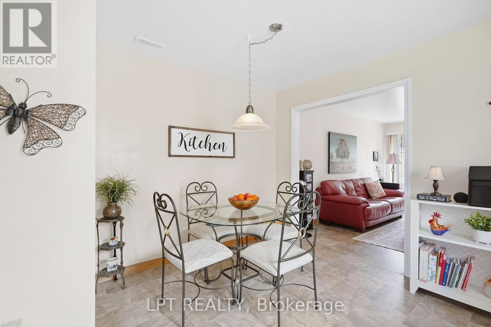 Dining area with glass table and metal chairs beside a living room with a red leather sofa.
