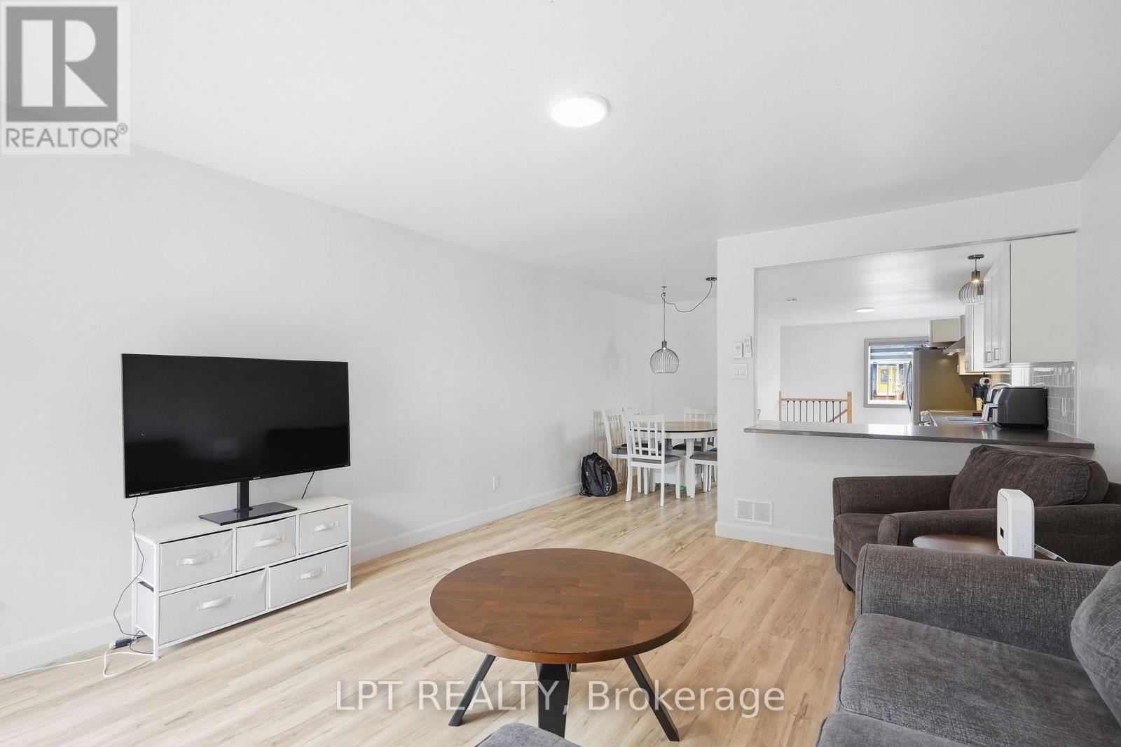 Living room with gray sofas, a round wooden coffee table, and an open dining area and kitchen.