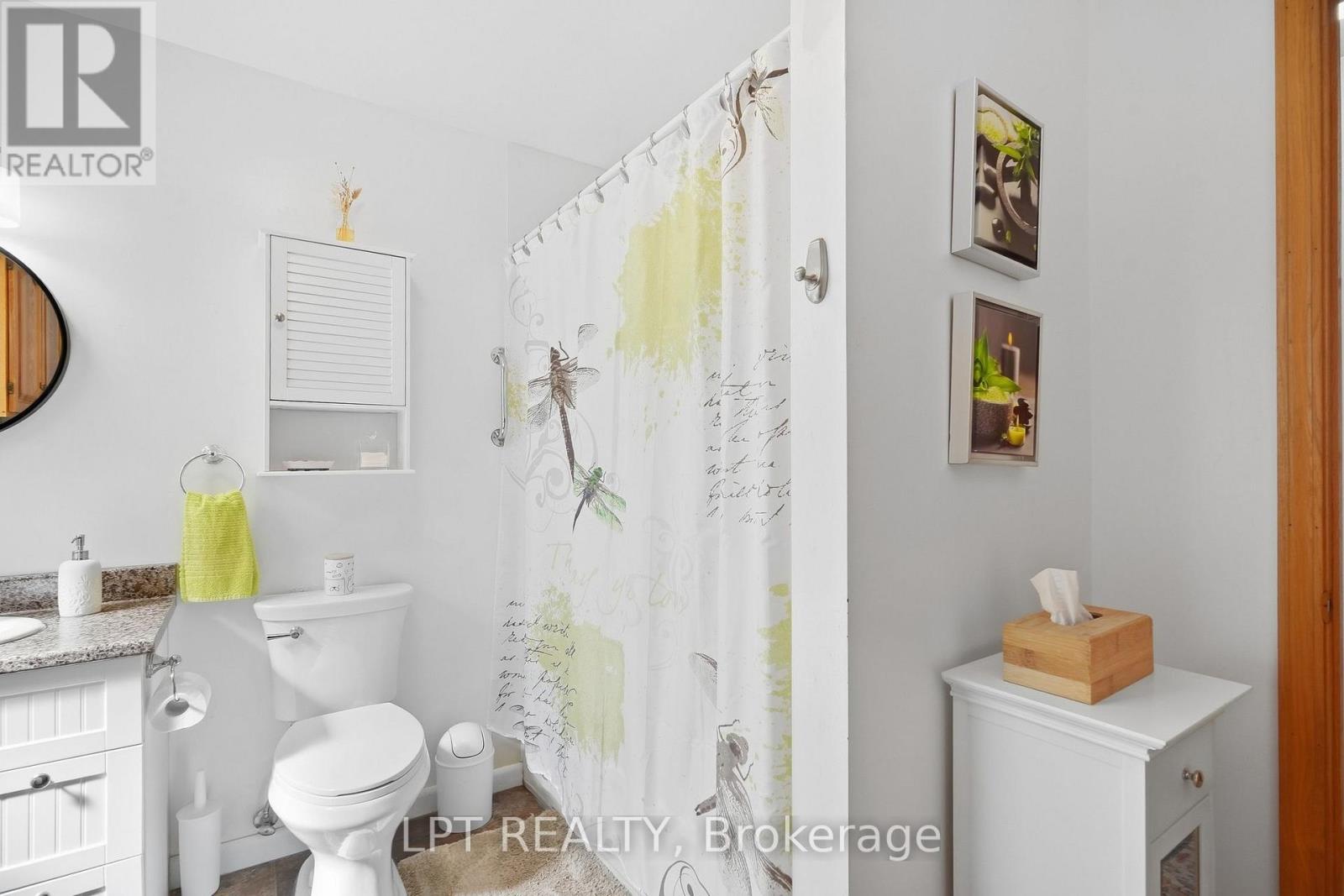 Bathroom with a patterned shower curtain, granite vanity, and white fixtures.