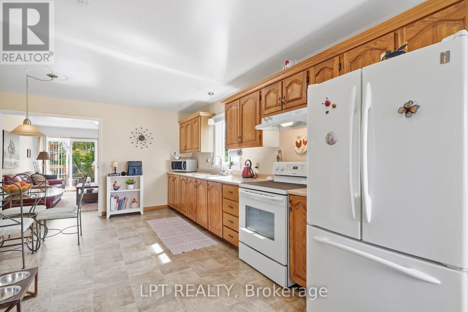 Kitchen with honey-colored wood cabinets, white appliances, and an open connection to the living area.