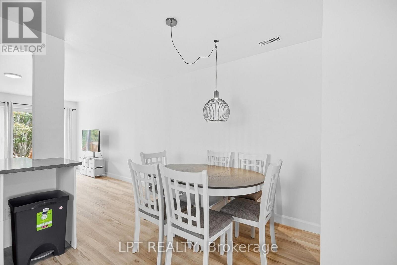 Dining area with a round wood table, white chairs, and a sculptural pendant light.