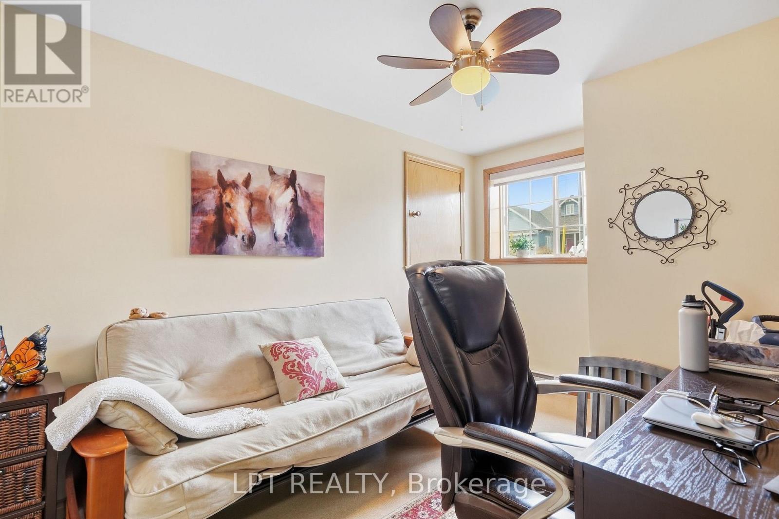 Furnished room with a cream sofa, leather recliner, desk, and ceiling fan.