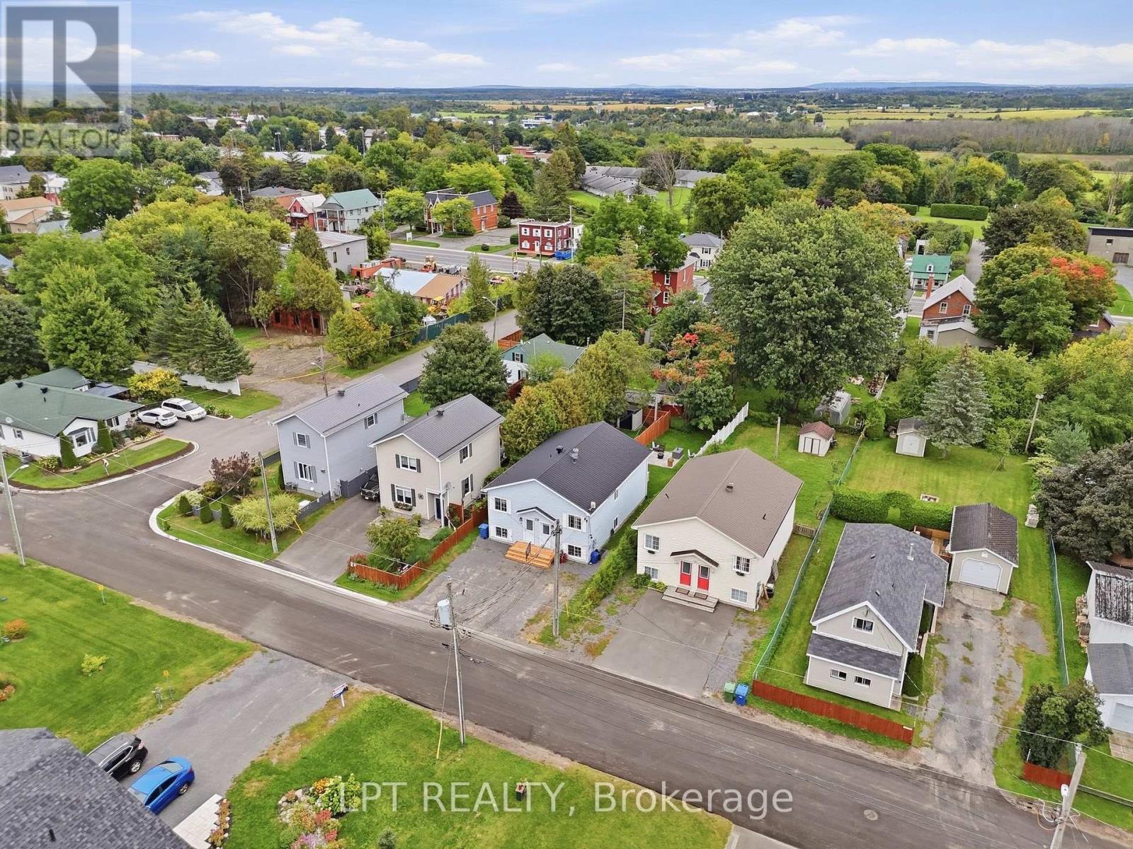 Aerial view of a leafy residential neighborhood, with detached homes and farmland stretching across the horizon.