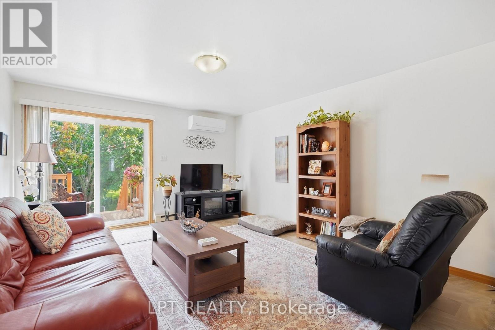 Furnished living room with leather seating, a patterned rug, and sliding glass doors to a deck.