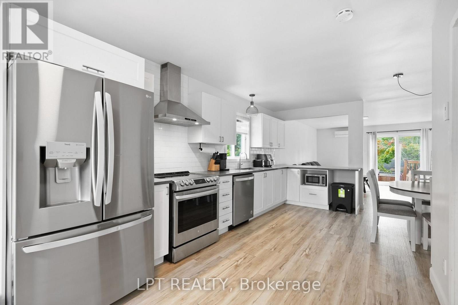 Open-concept kitchen with white cabinets, stainless-steel appliances, and an island beside the dining area.