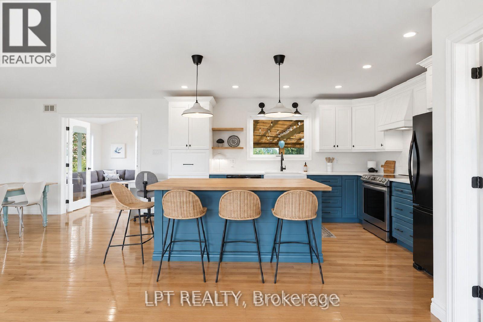 Bright kitchen with a blue island, wood countertop, and wicker stools.